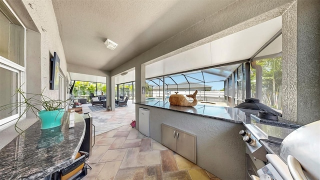 view of patio featuring glass enclosure, a grill, and area for grilling