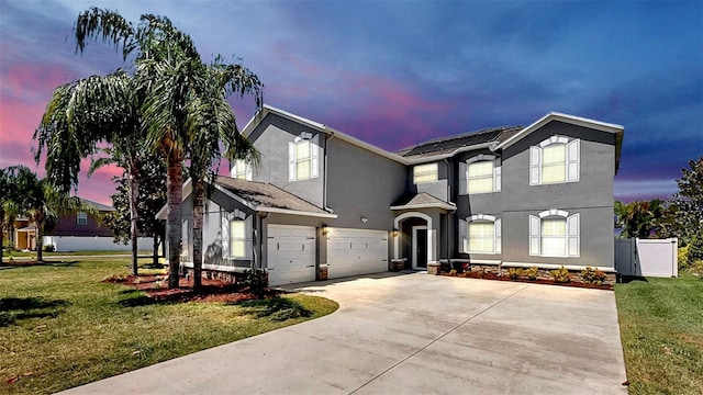 traditional-style home featuring a garage, stucco siding, a front yard, and concrete driveway