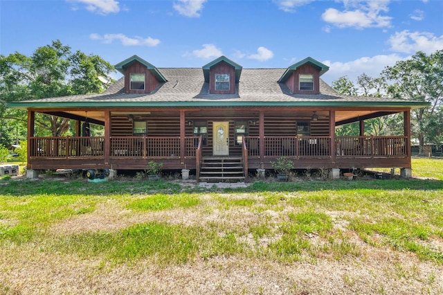 log cabin with a porch, roof with shingles, and a front lawn