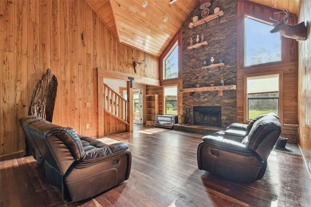 living area featuring stairs, wooden walls, wood-type flooring, and high vaulted ceiling