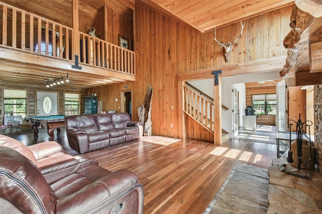 living area with stairs, wooden walls, pool table, and hardwood / wood-style flooring