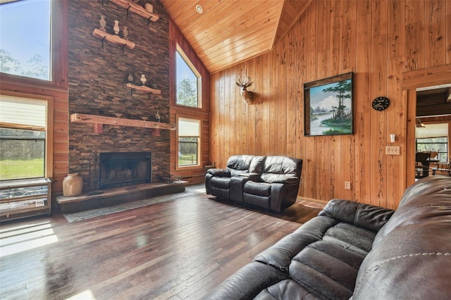 living area featuring a stone fireplace, wood ceiling, wooden walls, high vaulted ceiling, and hardwood / wood-style flooring