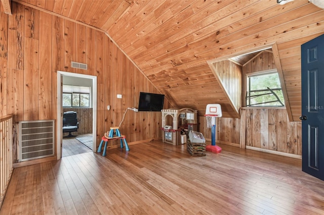 bonus room featuring plenty of natural light, visible vents, and wood walls