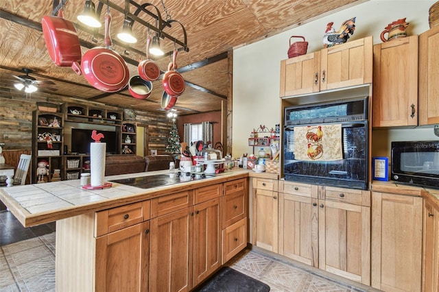 kitchen with a peninsula, black appliances, wooden ceiling, open floor plan, and tile counters