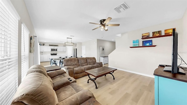 living room with visible vents, a ceiling fan, light wood-style flooring, and baseboards