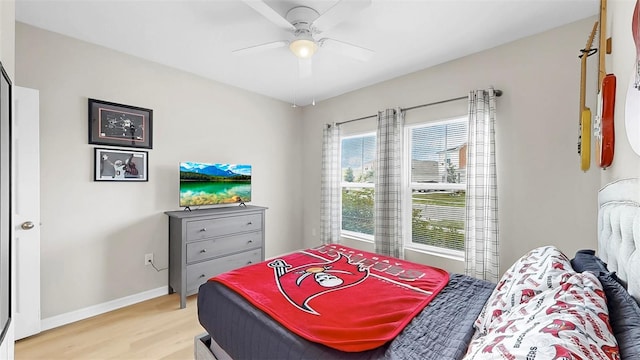 bedroom featuring baseboards, multiple windows, a ceiling fan, and light wood-type flooring