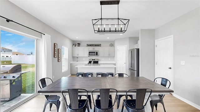 dining area with recessed lighting, baseboards, a notable chandelier, and light wood-style flooring
