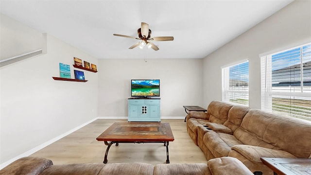 living room featuring baseboards, light wood finished floors, and ceiling fan