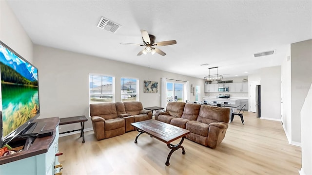 living area with a ceiling fan, light wood-type flooring, and visible vents