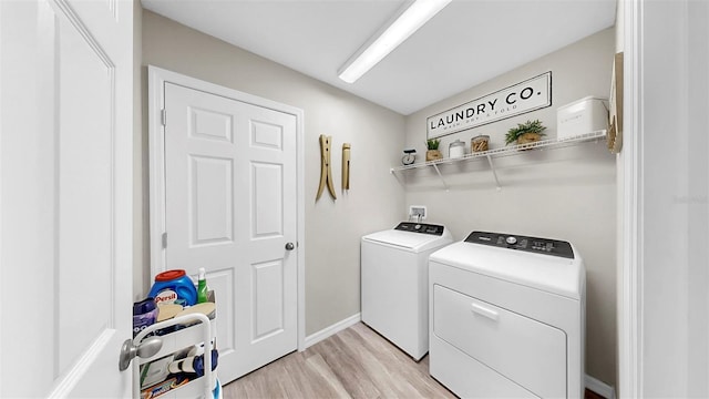 clothes washing area with independent washer and dryer, laundry area, baseboards, and light wood-style floors