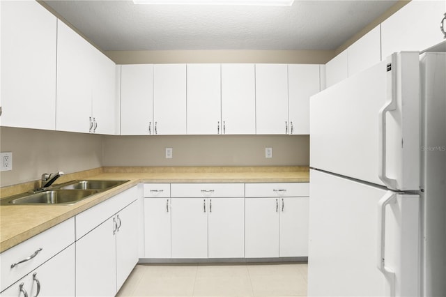 1750 Arabian Ln, Palm Harbor, FL 34685 - kitchen featuring freestanding refrigerator, a sink, light countertops, white cabinets, and a textured ceiling