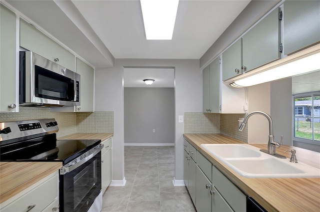 1516 Roundtree Rd, Holiday, FL 34690 - kitchen featuring decorative backsplash, baseboards, a sink, light tile patterned floors, and stainless steel appliances