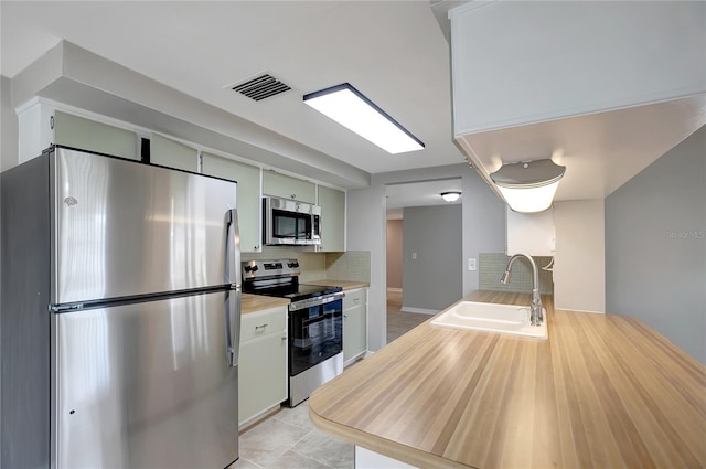1516 Roundtree Rd, Holiday, FL 34690 - kitchen with visible vents, decorative backsplash, light tile patterned flooring, a sink, and stainless steel appliances
