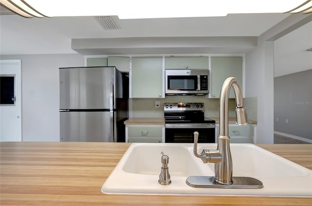 1516 Roundtree Rd, Holiday, FL 34690 - kitchen featuring visible vents, decorative backsplash, light countertops, a sink, and appliances with stainless steel finishes
