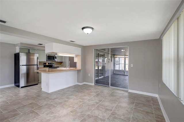 1516 Roundtree Rd, Holiday, FL 34690 - kitchen featuring visible vents, a peninsula, baseboards, light countertops, and appliances with stainless steel finishes