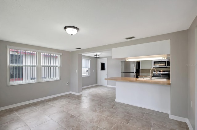 1516 Roundtree Rd, Holiday, FL 34690 - kitchen featuring visible vents, appliances with stainless steel finishes, a sink, baseboards, and light countertops