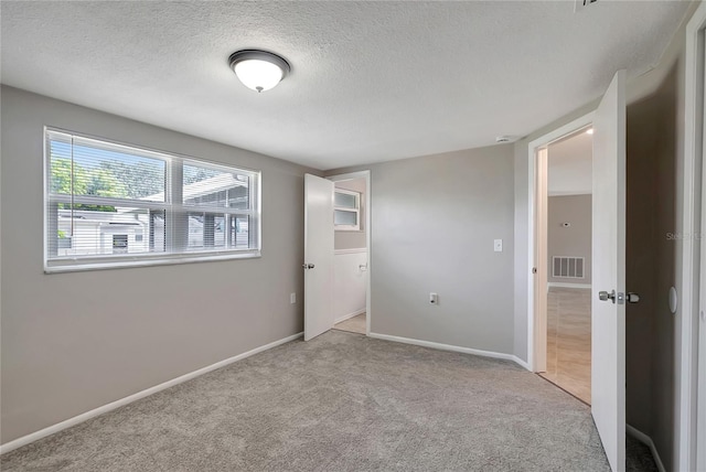 1516 Roundtree Rd, Holiday, FL 34690 - unfurnished room featuring baseboards, light colored carpet, a textured ceiling, and visible vents