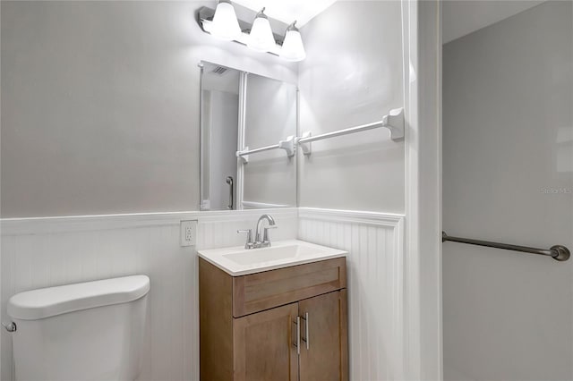 1516 Roundtree Rd, Holiday, FL 34690 - bathroom with vanity, a decorative wall, a wainscoted wall, and toilet