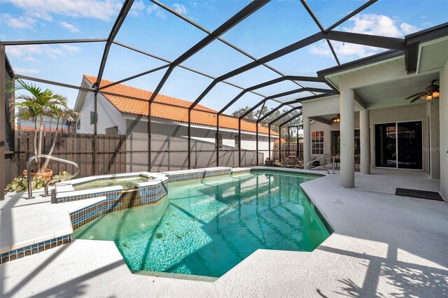 view of pool featuring glass enclosure, ceiling fan, a pool with connected hot tub, and a patio area