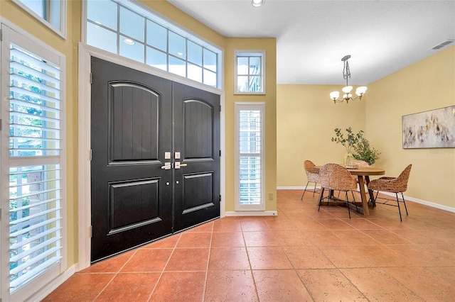 entrance foyer with baseboards, visible vents, an inviting chandelier, and tile patterned flooring