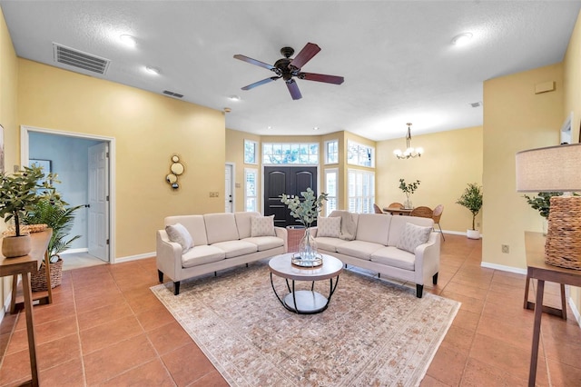 living area with baseboards, visible vents, light tile patterned floors, and ceiling fan with notable chandelier