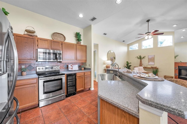 kitchen with appliances with stainless steel finishes, a sink, beverage cooler, lofted ceiling, and tasteful backsplash