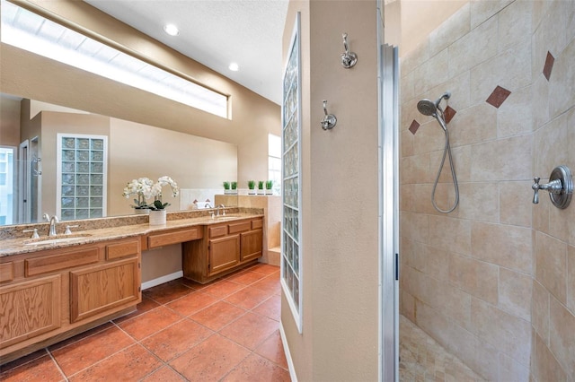 bathroom with double vanity, a tile shower, and a sink