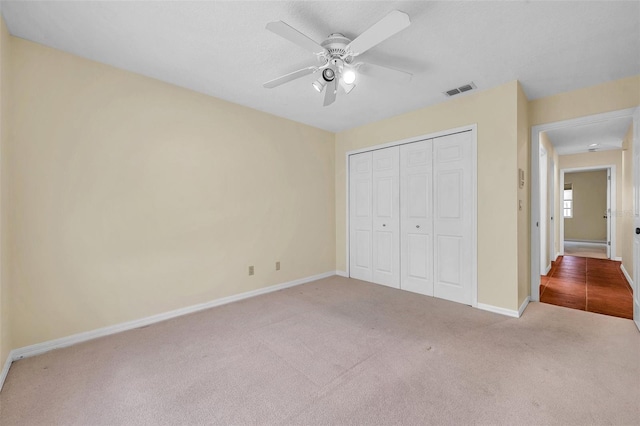 unfurnished bedroom featuring ceiling fan, visible vents, baseboards, a closet, and carpet flooring