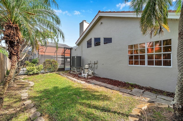 view of yard featuring fence, a lanai, and central AC unit