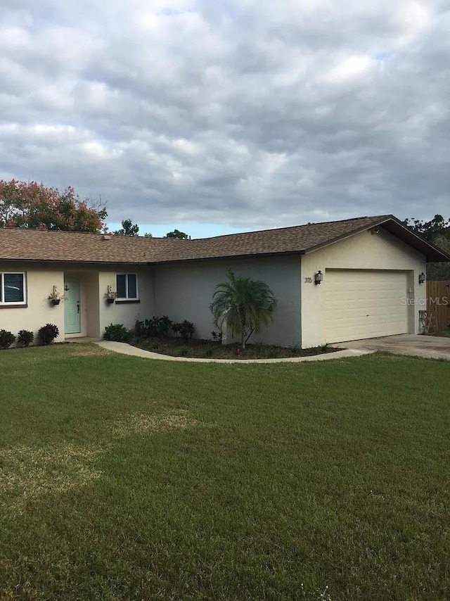 3115 Winchester Dr, Dunedin, FL 34698 - single story home featuring concrete driveway, stucco siding, an attached garage, and a front lawn