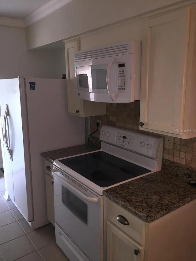 3115 Winchester Dr, Dunedin, FL 34698 - kitchen featuring light tile patterned floors, backsplash, white appliances, and white cabinetry