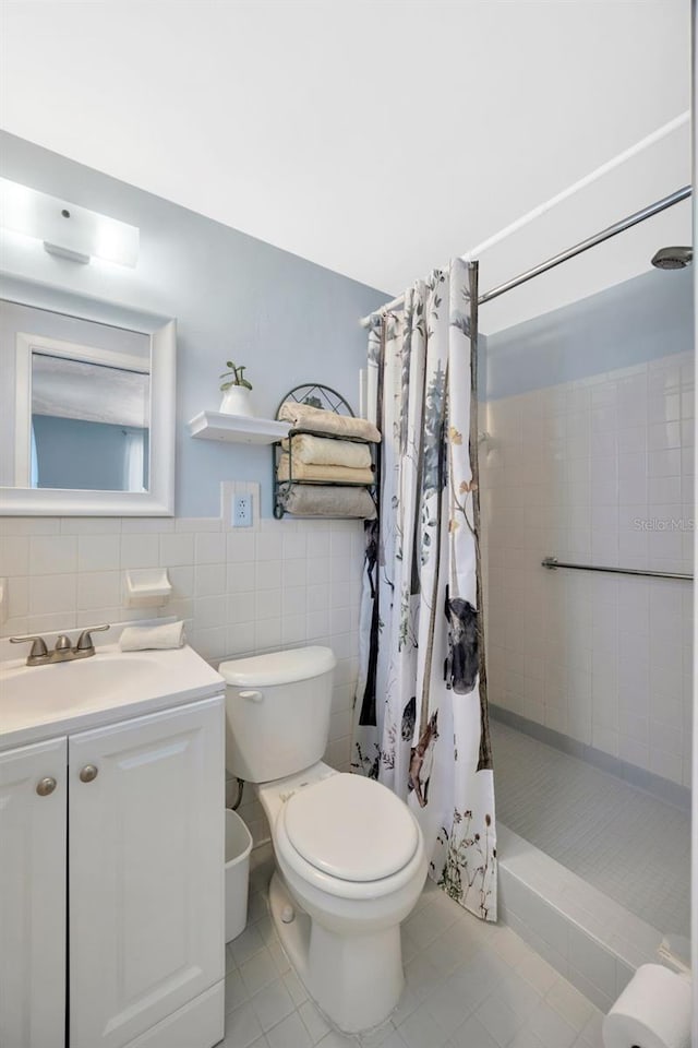 bathroom with vanity, toilet, tile patterned floors, tile walls, and tiled shower