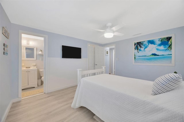 bedroom with light wood-style floors, a ceiling fan, and connected bathroom