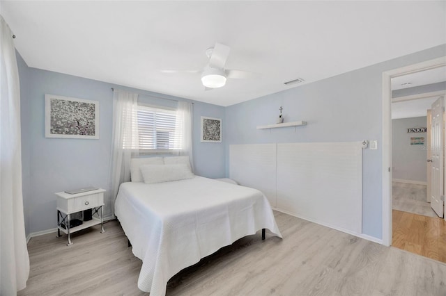 bedroom with a ceiling fan, baseboards, visible vents, and wood finished floors