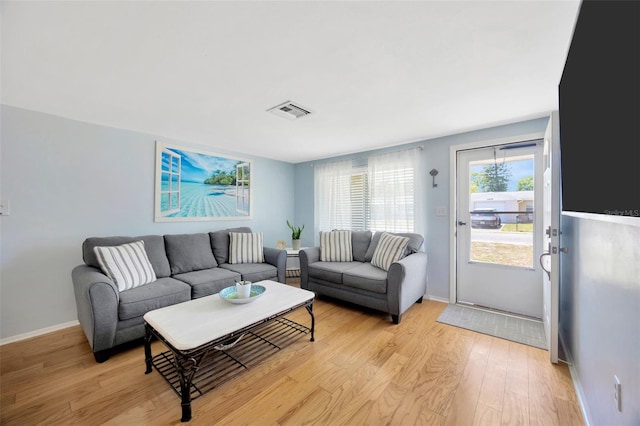 living area with baseboards, visible vents, and light wood-style flooring