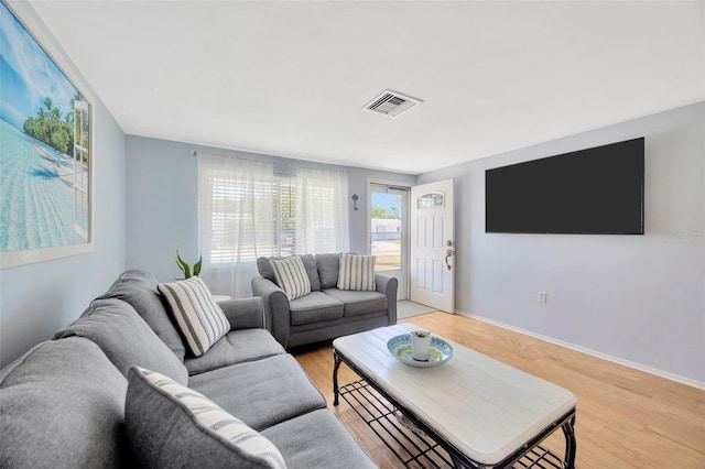 living area with baseboards, visible vents, and light wood-style floors