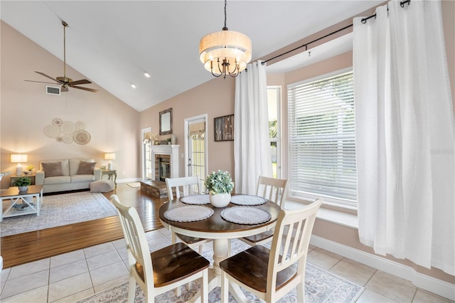 2512 Rustic Oaks Dr, Lutz, FL 33559 - dining room featuring light tile patterned floors, ceiling fan, a glass covered fireplace, a chandelier, and high vaulted ceiling
