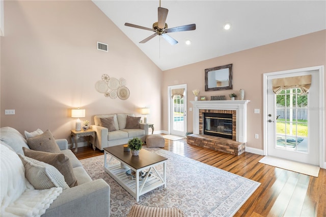 2512 Rustic Oaks Dr, Lutz, FL 33559 - living room featuring high vaulted ceiling, wood finished floors, a ceiling fan, a brick fireplace, and baseboards