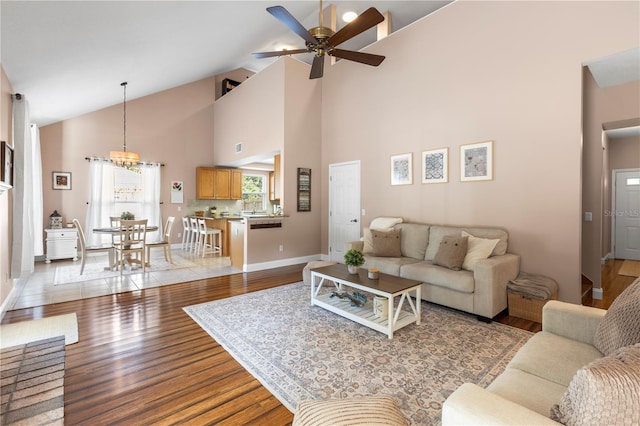 2512 Rustic Oaks Dr, Lutz, FL 33559 - living room with light wood-style floors, ceiling fan, high vaulted ceiling, baseboards, and a chandelier