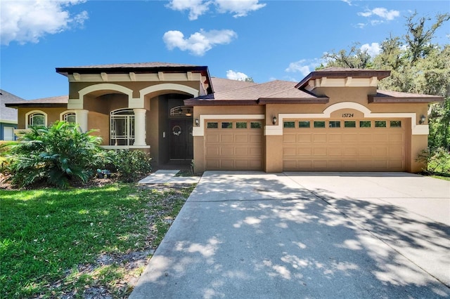 view of front facade with a garage, stucco siding, driveway, and a front lawn