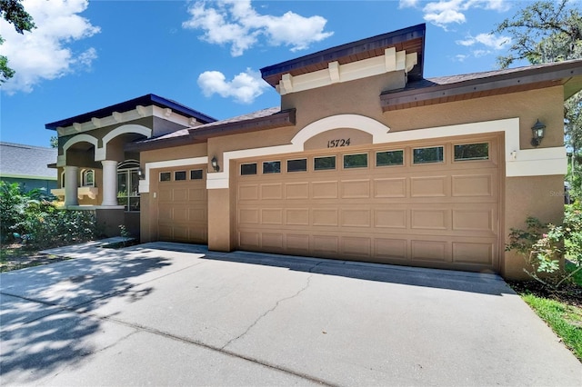 mediterranean / spanish house with stucco siding, an attached garage, and driveway