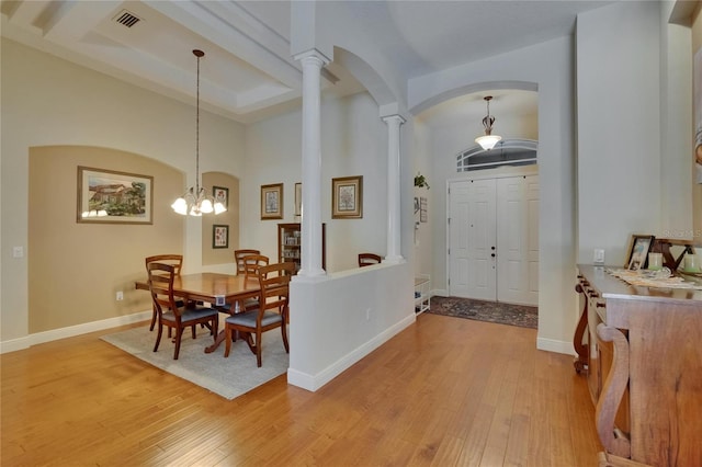 foyer with visible vents, arched walkways, light wood-type flooring, a chandelier, and ornate columns