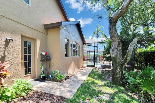 view of side of property featuring glass enclosure, an outdoor pool, and stucco siding