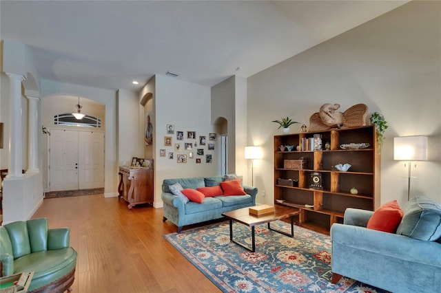 living room featuring visible vents, decorative columns, recessed lighting, arched walkways, and light wood-style flooring