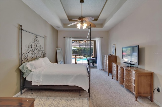 bedroom with access to outside, ceiling fan, light colored carpet, and a raised ceiling