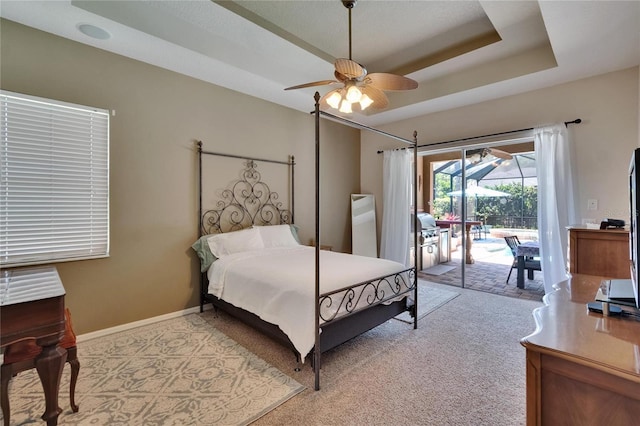 bedroom with light carpet, baseboards, access to outside, a raised ceiling, and a ceiling fan