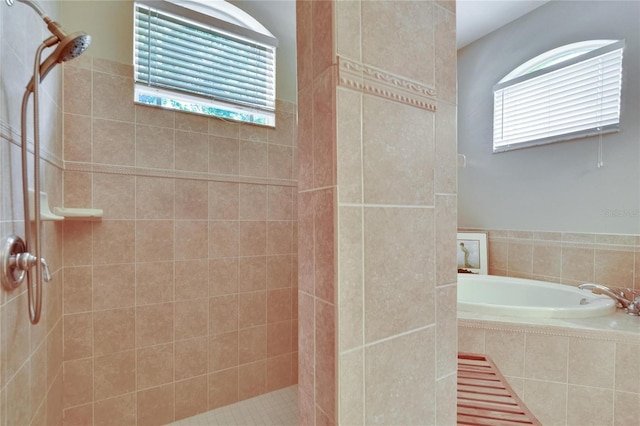 full bathroom with a bath and a tile shower