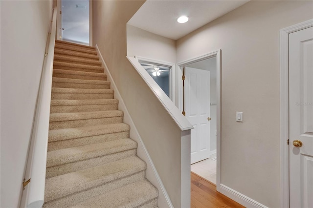 stairs featuring a ceiling fan, baseboards, and wood finished floors