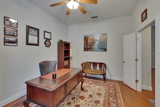 office space featuring light wood-style floors, baseboards, ceiling fan, and visible vents