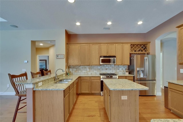 15724 Ibisridge Dr, Lithia, FL 33547 - kitchen with a sink, appliances with stainless steel finishes, light brown cabinetry, and a breakfast bar area